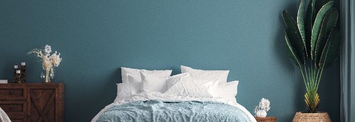 Bett vor blauer Wand mit Pflanze